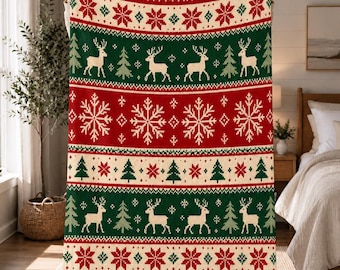Könnte beinhalten: Eine rechteckige Strickdecke mit einem festlichen Weihnachtsmuster aus abwechselnden horizontalen Streifen in Rot, Creme und Dunkelgrün. Das Design zeigt wiederkehrende Motive von weißen Rentieren, Tannenbäumen und komplexen Schneeflocken.