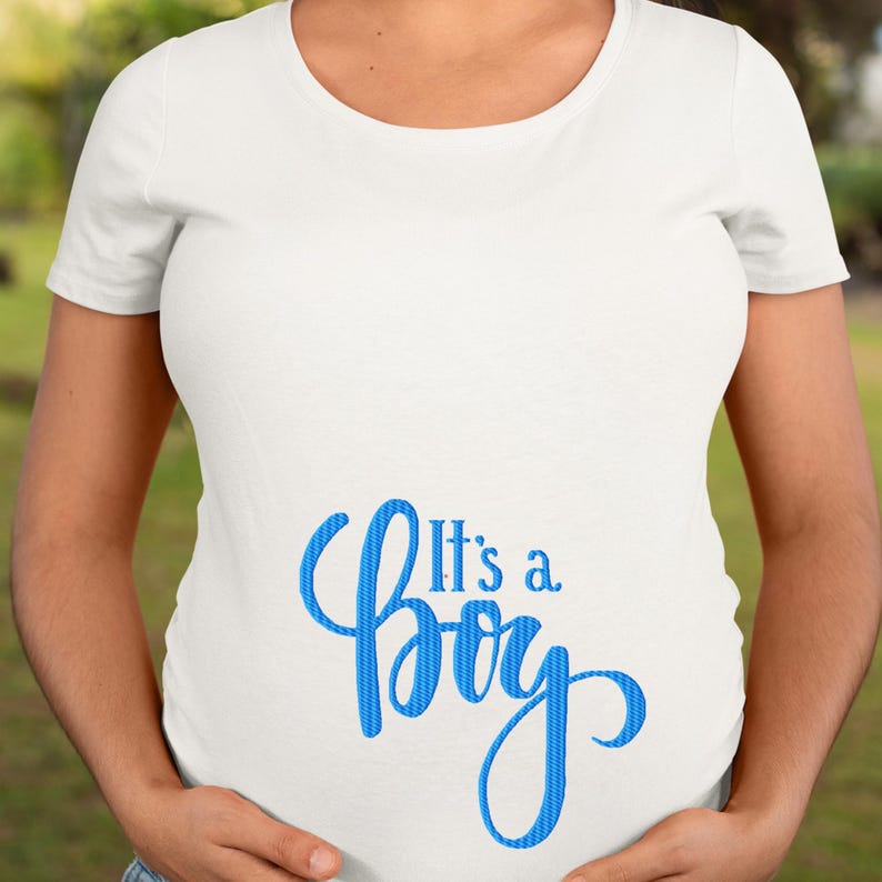 May include: White t-shirt with the blue text "It's a Boy" in a script font. The shirt is a crew neck style and appears to be made of a soft material. The text is centered on the lower front of the shirt.