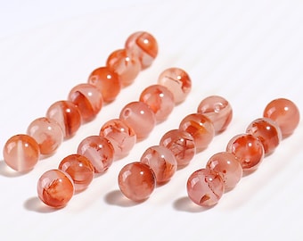 May include: A strand of red agate beads with white marbling. The beads are round and smooth, and they are arranged in a line.
