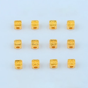 Puede incluir: Doce cuentas de metal de color dorado con un diseño decorativo. Las cuentas son de forma cuadrada y tienen un acabado liso y brillante.
