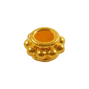 May include: A gold bead with a round, slightly raised center and a ring of small, round beads around the edge.