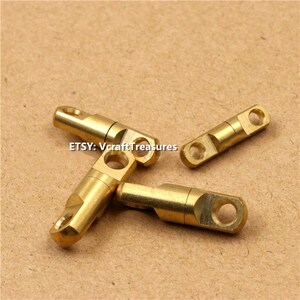 May include: Three gold-colored swivel snap hooks with a small hole at each end. The hooks are made of metal and have a smooth, polished finish.