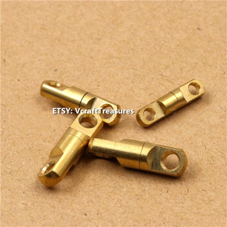 May include: Three gold-colored swivel snap hooks with a small hole at each end. The hooks are made of metal and have a smooth, polished finish.