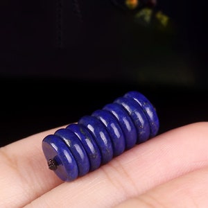 May include: A stack of dark blue lapis lazuli beads, each bead is round and has a smooth, polished surface.