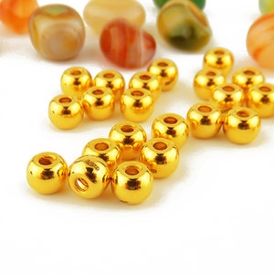 May include: A group of 20 gold-colored round beads. The beads are shiny and have a smooth surface.