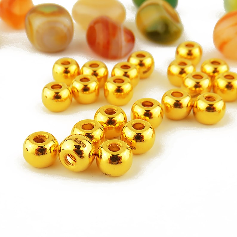 May include: A group of 20 gold-colored round beads. The beads are shiny and have a smooth surface.