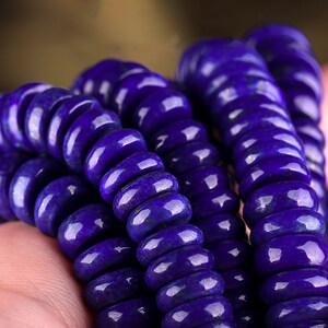 May include: A strand of deep blue lapis lazuli beads, each bead is round and slightly flattened, creating a unique and textured look.