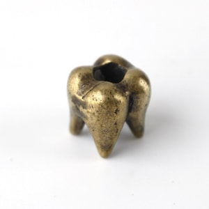 May include: A small, gold-colored metal tooth-shaped incense holder with four legs.