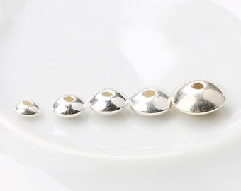 May include: Five silver-toned metal beads of varying sizes, arranged in order from smallest to largest.