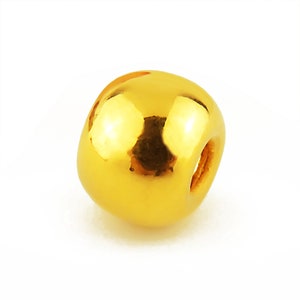May include: A solid gold bead with a smooth, shiny surface. The bead has a small hole drilled through the center.