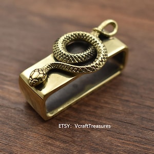 May include: A brass key chain with a snake design. The snake is coiled around a rectangular brass bar. The key chain is a great way to add a touch of style to your keys.