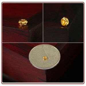 May include: A small, gold-colored bead with a textured surface. The bead is about the size of a dime.