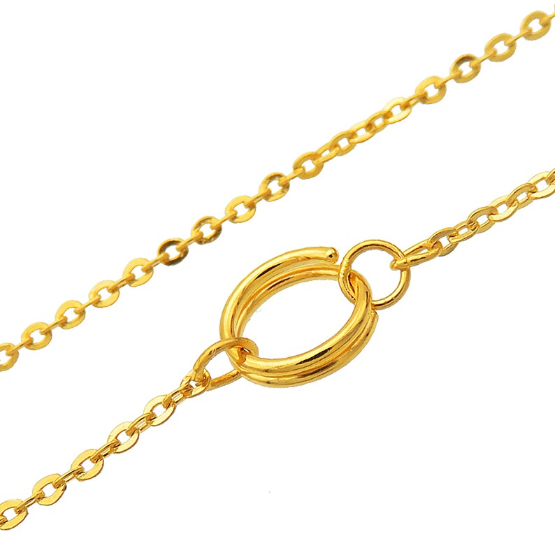 K&ouml;nnte beinhalten: Eine goldene Kettenkette mit einem Doppelringverschluss. Die Kette ist in einem zarten Kabeldesign.