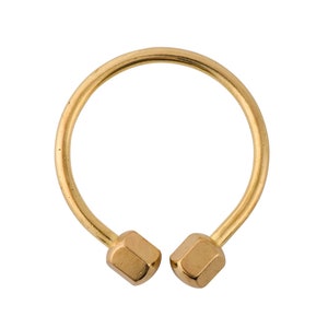 May include: A gold-colored metal ring with two hexagonal ends. The ring is open and has a smooth, rounded surface.