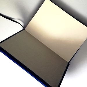 May include: A blue leather-bound journal with a blank page open. The journal has a black ribbon bookmark.