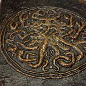 Puede incluir: Un diario de cuero marr&oacute;n oscuro con un dise&ntilde;o en relieve de un &aacute;rbol con ra&iacute;ces y ramas en color cobre.