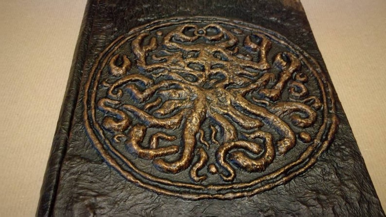 Puede incluir: Un diario de cuero marr&oacute;n oscuro con un dise&ntilde;o en relieve de un &aacute;rbol con ra&iacute;ces y ramas en color cobre.