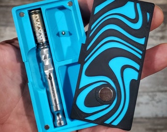 May include: A blue and black patterned case with a magnetic closure. The case is open to reveal a silver Dynavap vape tool. Dynavap Not Included. Picture For Display Purposes Only.