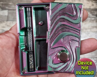 May include: A multi-colored case with a wave pattern in shades of green, pink, and purple, with a silver button. The case is open, revealing a compartment with a Dynavap device. The text "Device Not Included!" is visible.
