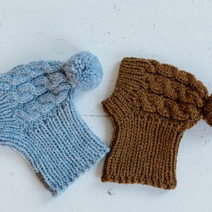May include: Two knitted hats with pom-poms. One hat is light blue and the other is brown.