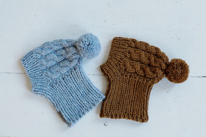 May include: Two knitted hats with pom-poms. One hat is light blue and the other is brown.