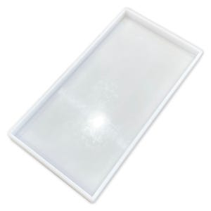 May include: A rectangular, white silicone mould with raised edges. The mould is empty and appears clean, with a slightly reflective surface. The design is simple and functional, suitable for crafting or casting projects.