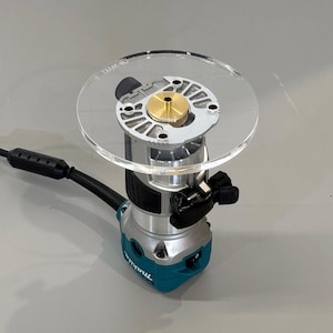 May include: A blue and silver router with a clear plastic base. The router is attached to a clear plastic circle with a brass center.