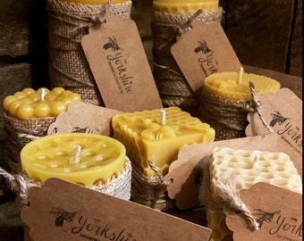 May include: A collection of pure beeswax candles in various shapes and sizes, including honeycomb, round, and pillar styles. The candles are wrapped in burlap and have a rustic, natural aesthetic. The candles are labeled with the text "The Yorkshire Beeswax Candle Co."