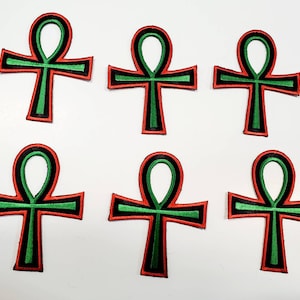 May include: Six green and red embroidered Ankh symbols with black outlines. The Ankh is an ancient Egyptian hieroglyphic symbol that represents life.