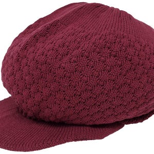 May include: A burgundy knit cap with a short brim. The cap has a textured pattern and is made of a soft, knitted material. This style of cap is often referred to as a newsboy or baker boy hat.