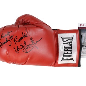 Puede incluir: Guante de boxeo de cuero rojo firmado por Mike Tyson con la inscripción "Let's Get Ready to Rumble!" y el logotipo de Everlast. El guante viene acompañado de una tarjeta de autenticación JSA.