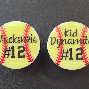May include: Two yellow and red softball-themed phone grips with glitter. One grip says "Mackenzie #12" and the other says "Kid Dynamite #12".
