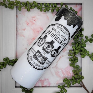 May include: White and black tumbler with a black bat apothecary design. The design features a black bat with the words "Black Bat Apothecary" and a variety of potion bottles with labels that say "Mystical Brews", "Fine Potions", "Magical Charms", and "Powders & Elixirs".