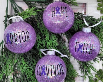 May include: Four purple glitter Christmas ornaments with white ribbon hangers. Each ornament has a purple ribbon and a word printed in black: "Hope", "Warrior", "Faith", and "Survivor".