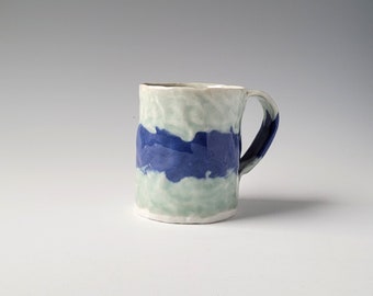 Mug with celadon glaze over blue colored porcelain stripe
