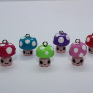 May include: A collection of six colorful mushroom charms. Each mushroom has a different colored cap, including red, blue, green, purple, and pink, with white polka dots. The mushroom stems are light pink with smiling faces and silver loops.