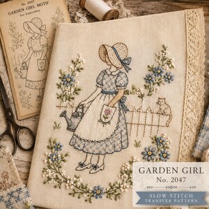 May include: Embroidered Garden Girl motif on cream fabric, featuring a girl with a watering can, surrounded by flowers and a cat. The design includes the text "GARDEN GIRL No. 2047" and "SLOW STITCH TRANSFER PATTERN".