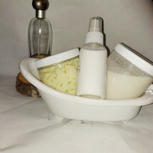 Puede incluir: Tres recipientes blancos con tapas, uno con una boquilla de pulverizaci&oacute;n, en un plato blanco con forma de ba&ntilde;era. El recipiente de la izquierda contiene una sustancia amarilla, el recipiente del centro es una botella de pulverizaci&oacute;n y el recipiente de la derecha contiene una sustancia blanca.