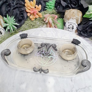 May include: A clear glass tray with two small white bowls and a black and white goat head design. The tray has black metal accents and the words "Requiem Resin" are printed on a white sticker.