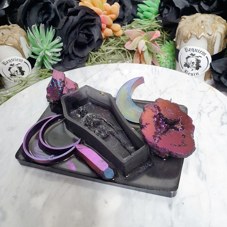 May include: Black tray with a coffin, two crescent moons, a crystal, and a large amethyst geode. The tray is made of resin and has a glossy finish.