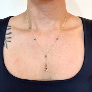 Curved gold disk drop pendant necklace with iridescent green crystal accents