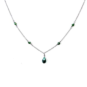 May include: A delicate silver chain necklace with a teardrop-shaped green crystal pendant and small green crystal accents.