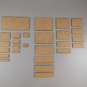 May include: A set of 16 brown wooden craft shapes, including squares and rectangles, arranged in a pattern on a grey background.