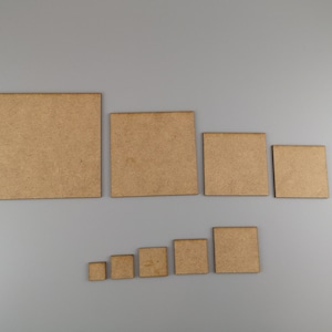 May include: Seven square wooden tiles of different sizes are displayed on a grey background. The tiles vary in size, with a natural wood grain finish. The largest tile is approximately 30 cm square, and the smallest is about 5 cm square. Ideal for crafts or DIY projects.