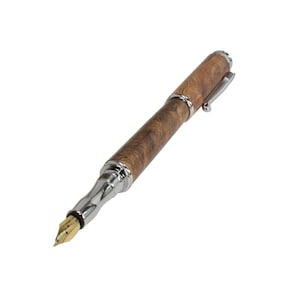 Puede incluir: Una pluma estilogr&aacute;fica de madera marr&oacute;n con cuerpo de metal plateado y plum&iacute;n de oro.