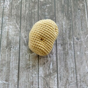 May include: A beige crocheted beanie hat on a woodgrain background.
