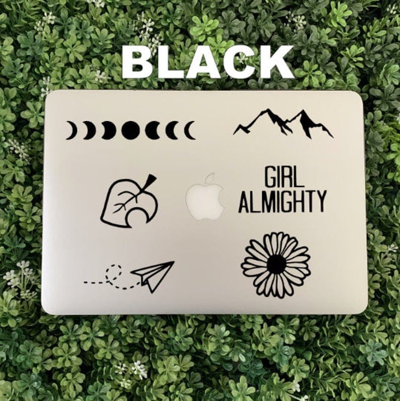 Pu&ograve; includere: Un laptop bianco con adesivi neri. Gli adesivi includono una catena montuosa, una foglia, una mezzaluna, una margherita, un aeroplano di carta e il testo "Girl Almighty".