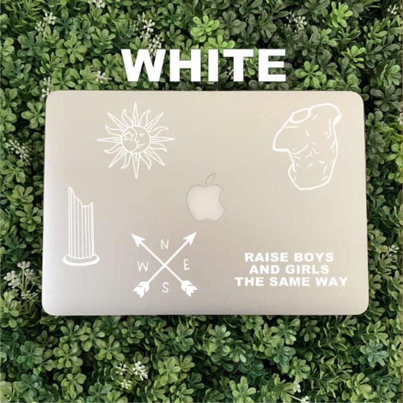 Pu&ograve; includere: Laptop bianco con diversi adesivi. Gli adesivi includono una bussola, un sole, una colonna, una figura e un testo che recita "Allevare i ragazzi e le ragazze allo stesso modo."