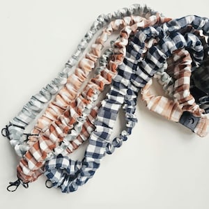 Peut inclure: Une collection de sangles élastiques recouvertes de tissu avec des motifs vichy bleu marine, terre cuite et vert sauge. Chaque sangle comprend une boucle à dégagement latéral en plastique noir et un mousqueton pivotant en métal.