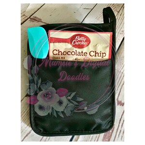 May include: Black oven mitt with a floral design and a pocket that holds a blue spatula and a Betty Crocker Chocolate Chip Cookie Mix box.